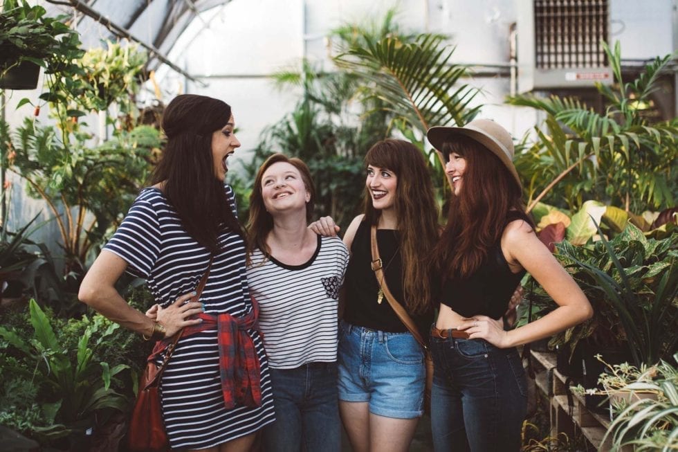 Group of four women embracing and smiling