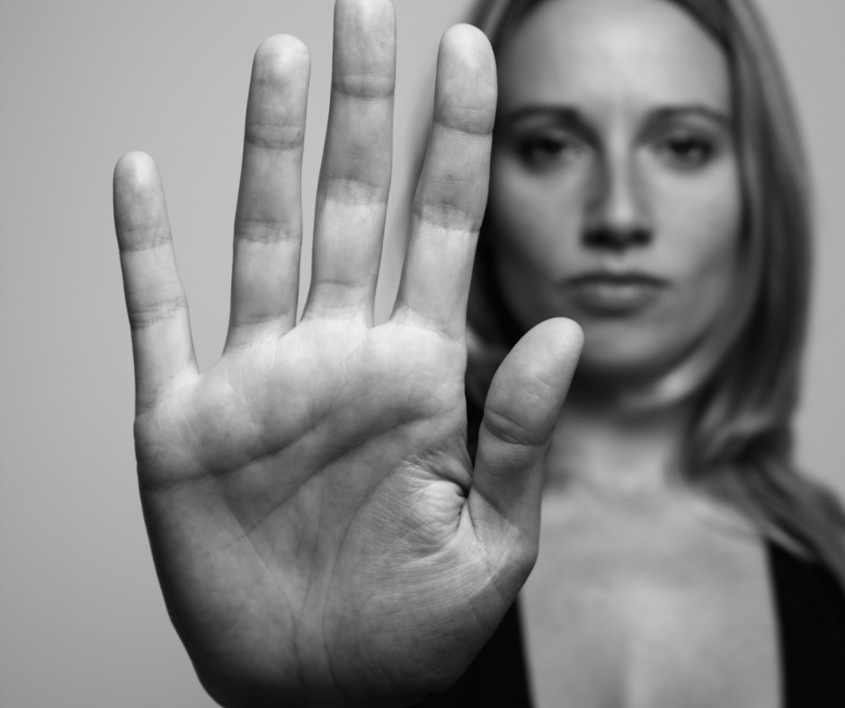 Black and white photo of woman holding up her palm in the stop position